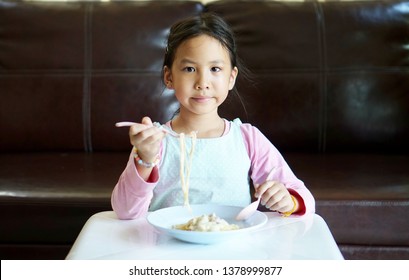 Little Asian Girl Eating Spaghetti On Table At Home