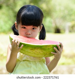 Little Asian Girl Eating Watermelon In Park