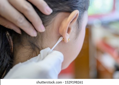 Little Asian Girl Having Ear Piercing Process.