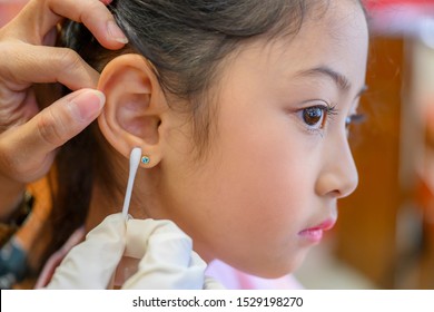 Little Asian Girl Having Ear Piercing Process.