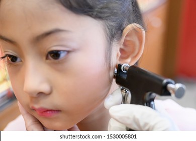 Little Asian Girl Having Ear Piercing Process.