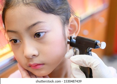 Little Asian Girl Having Ear Piercing Process.