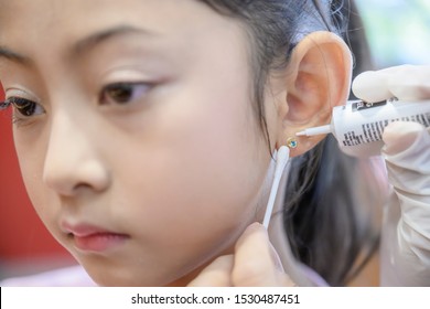 Little Asian Girl Having Ear Piercing Process.