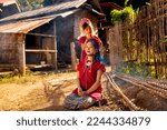Little Asian girl help to set and decorate hair of her older sister and stay near road in Long Neck Karen Village in Thailand with warm light.