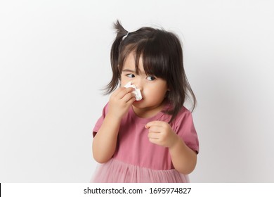 Little Asian Girl Holding A Tissue And Blow Her Nose. Kid With Cold Rhinitis. Virus And Infection. Coronavirus Symptom