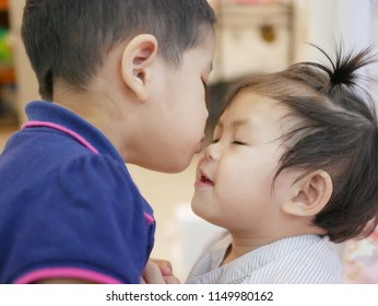 Little Asian girl kissing her younger baby sister - children's early relationships: siblings and friends - Shutterstock ID 1149980162