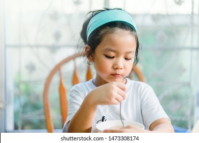 Little Asian Girl Make Boring Face When She Eat Breakfast.Unhappy, Disgusted, Unlike Food In The Morning Concept.Little Asian Girl Child With No Appetite In Front Of The Meal.