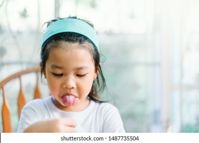 Little asian girl make boring face and tongue out when she eat breakfast.Unhappy, Disgusted, Unlike food in the morning concept.Little asian girl child with no appetite in front of the meal.