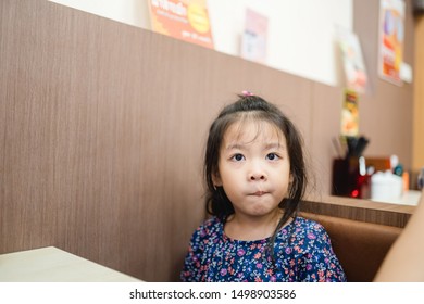 Little Asian Girl Make Boring Face When She Eat Breakfast.Unhappy, Disgusted, Unlike Food In The Morning Concept.Little Asian Girl Child With No Appetite In Front Of The Meal.