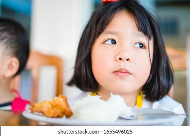 Little Asian Girl Make Boring Face When She Eat Vegetable In Breakfast.Unhappy, Disgusted, Unlike Food In The Morning Concept.Little Asian Girl Child With No Appetite In Front Of The Meal.