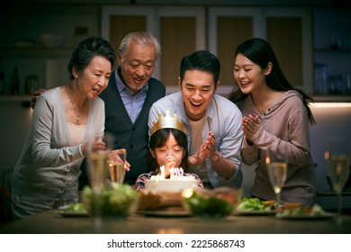 little asian girl making a wish while three generation family celebrating her birthday at home - Powered by Shutterstock