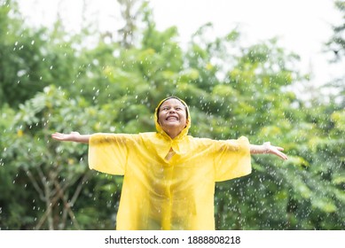 Little Asian Girl Play In Autumn Rain. Kid Playing On The Nature Outdoors. Girl Is Wearing Yellow Raincoat And Enjoying Rainfall. Family Walk In The Park. Family Walk In The Park.