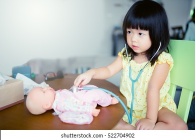 Little Asian Girl Play With Baby Doll Toy.Little Asian Girl Hold Stethoscope In Hand And Check Baby Doll Toy.