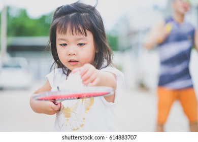 Little Asian Girl Playing Badminton With Her Father In Front Of The House.