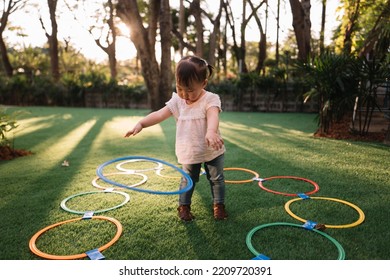 Little Asian Girl Playing Hula Hoop In The Garden