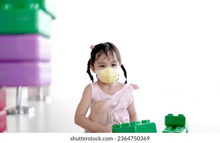 Little asian girl playing indoors building a house with big plastic construction bricks - Shutterstock ID 2364750369