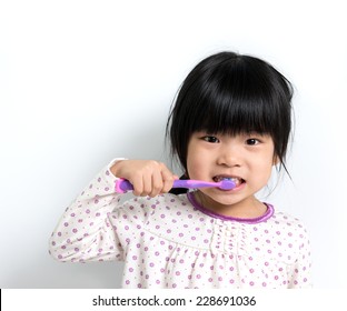 Little Asian Girl In Pyjamas Brushing Teeth