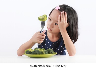 Little Asian girl refuse to eat healthy vegetables.
