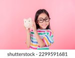 Little Asian girl saving money in a piggy bank, learning about saving, Kid save money for future education. Money, finances, insurance, and people concept