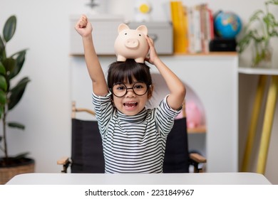 Little Asian girl saving money in a piggy bank, learning about saving, Kid save money for future education. Money, finances, insurance, and people concept - Powered by Shutterstock