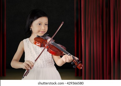 Little Asian Girl Showing Her Talent By Playing A Song With A Violin On The Stage