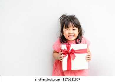 Little Asian Girl Smile And Holding Red Gift Box On White Background.child Holding Gift Box On Birthday.Merry Christmas.present Box.Asian Child Girl Toddler Baby Smile Surprise On Her Birthday.