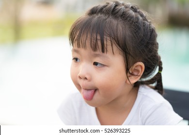 little asian girl toung out in playground.