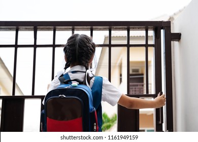 Little Asian Girl In Uniform Opening The Door For Leaving To School In The Morning With Blue Back Pack