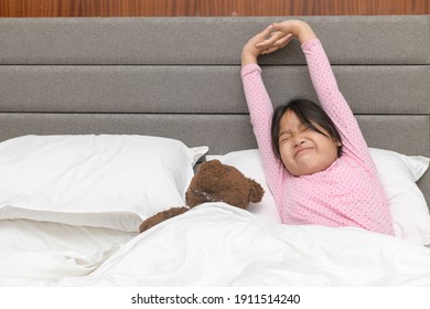 Little asian girl wakes up and stretching on bed in morning, Health care and good morning world concept
