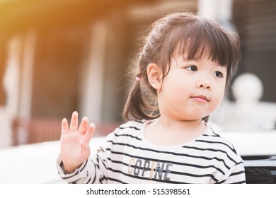 Little Asian Girl Waving Her Hand Saying Goodbye In The Car.Sunset Time.