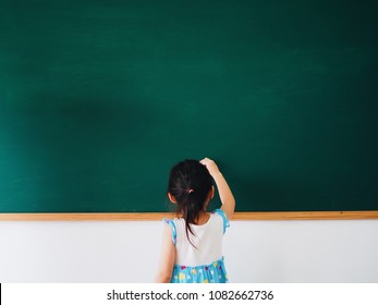 Little Asian Girl Writing On Chalkboard.