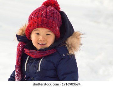 Little Asian (Kazakh) boy is playing in the snow in winter clothes.