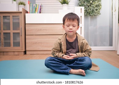 Little Asian Kid With Eyes Closed, Barefoot Practices Yoga & Meditating To Relieve Negative Emotions On Weekend At Home, Beginner Meditation, Breathing Exercise For Kids, Healthy Lifestyle Concept