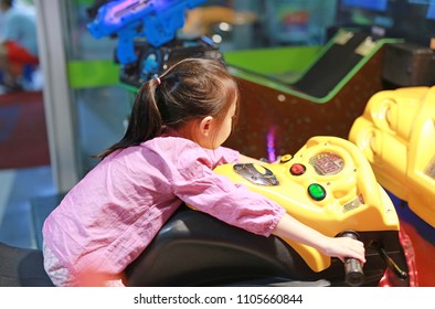 Little Asian kid girl playing arcade video game. Motorcycle Racing.