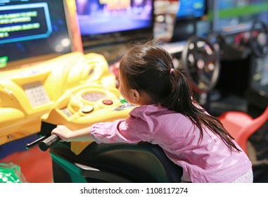 Little Asian kid girl playing arcade video game. Motorcycle Racing.