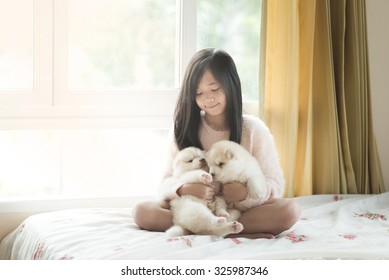 Little asian playing with siberian husky puppies on the bed,vintage filter - Shutterstock ID 325987346