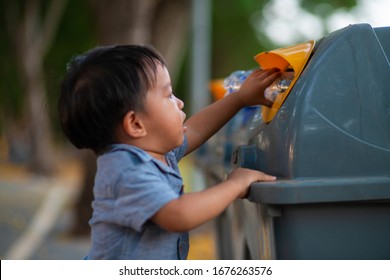 Little asian toddler baby boy throwing plastic bottle in recycling trash bin at public park, Eco friendly kid Recycling, Save the world & environment concept.