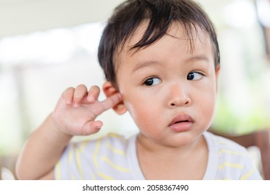 Little asian toddler baby boy has earache when insects inside outdoor baby infant boy hands touching in ear and pain.deaf kid.Flu and sick.Clean up earwax.Accident in kid with ear.Condition and clean. - Shutterstock ID 2058367490