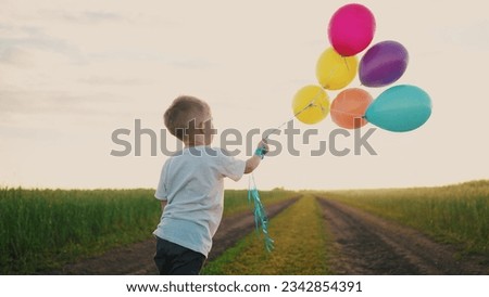 little baby boy with balloons. happy family a birthday kid dream concept. baby son holding balloons against a blue sky in park in nature. child playing with balloons on his birthday lifestyle