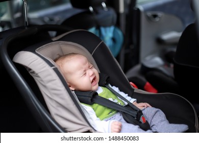 Little Baby Boy Is Crying While Sitting Inside Car Fastened In Safety Car Seat. Mixed Race Kid Asian-German 3months Old.