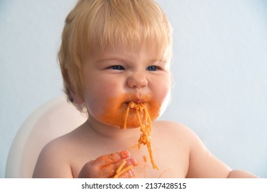 Little Baby Boy Eating Spaghetti Bolognese. Cute Kid Making A Mess. Close Up Portrait