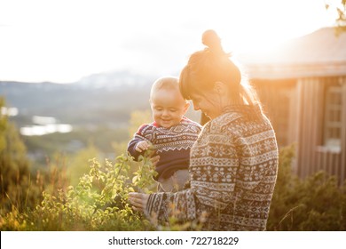 Little baby boy with her young mother having fun outside in the countryside in Norway in the National park Hardangervidda at sunset with warm red light. Blurred background. - Powered by Shutterstock