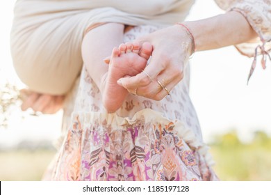 Little baby boy and his mother walking in the fields. Mother is holding and tickling her baby, babywearing in sling