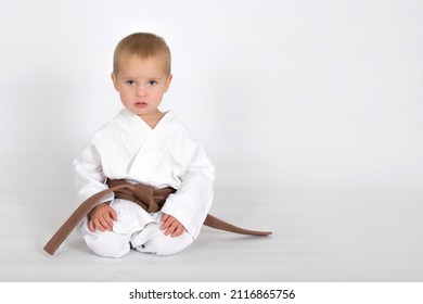 Little baby boy in karate kimono isolated on white background. The concept of martial arts, karate, judo,  sports since childhood, discipline. Defence concept with copy space.