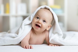 Little Baby Boy Lies On Belly Smiling Under White Towel