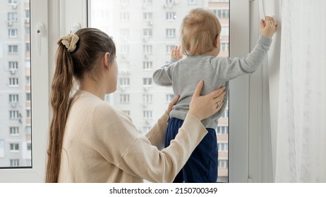 Little Baby Boy With Mother Looking Out Of The Window Of High Store Building