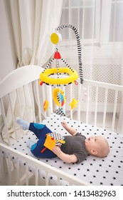 Little Baby Boy Playing With Baby Mobile And Toy In The Bed