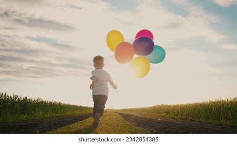 little baby boy run with balloons in the park in nature. happy family holiday birthday kid dream concept sun. little baby with colorful balloons run with the road lifestyle in the field park - Powered by Shutterstock