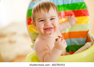 Little Baby Boy Sitting In A Bright Chair, Eating Strawberries And Contagious Laugh