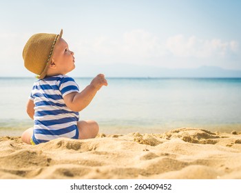 Kleiner kleiner, auf dem Sand sitzender Junge